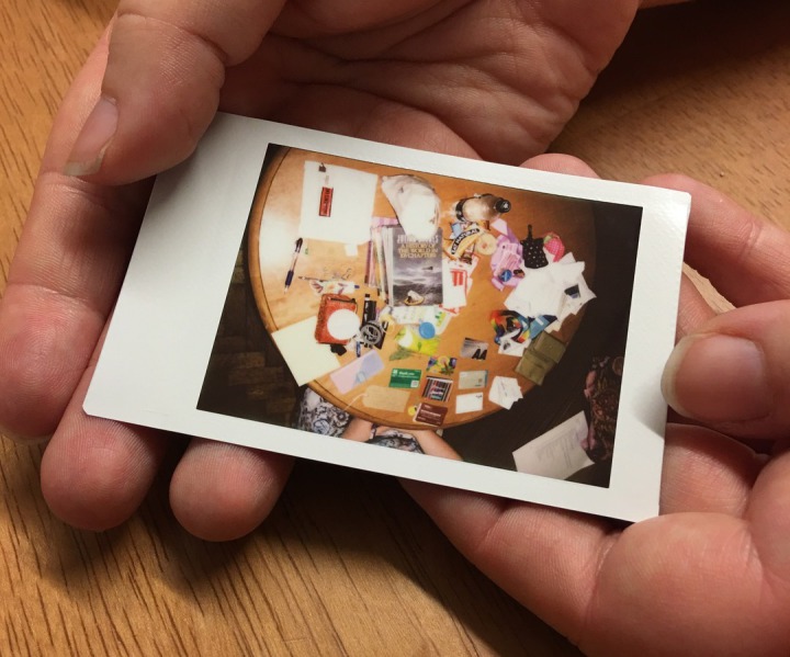 a hand holding a polaroid picture of the contents of a bag
